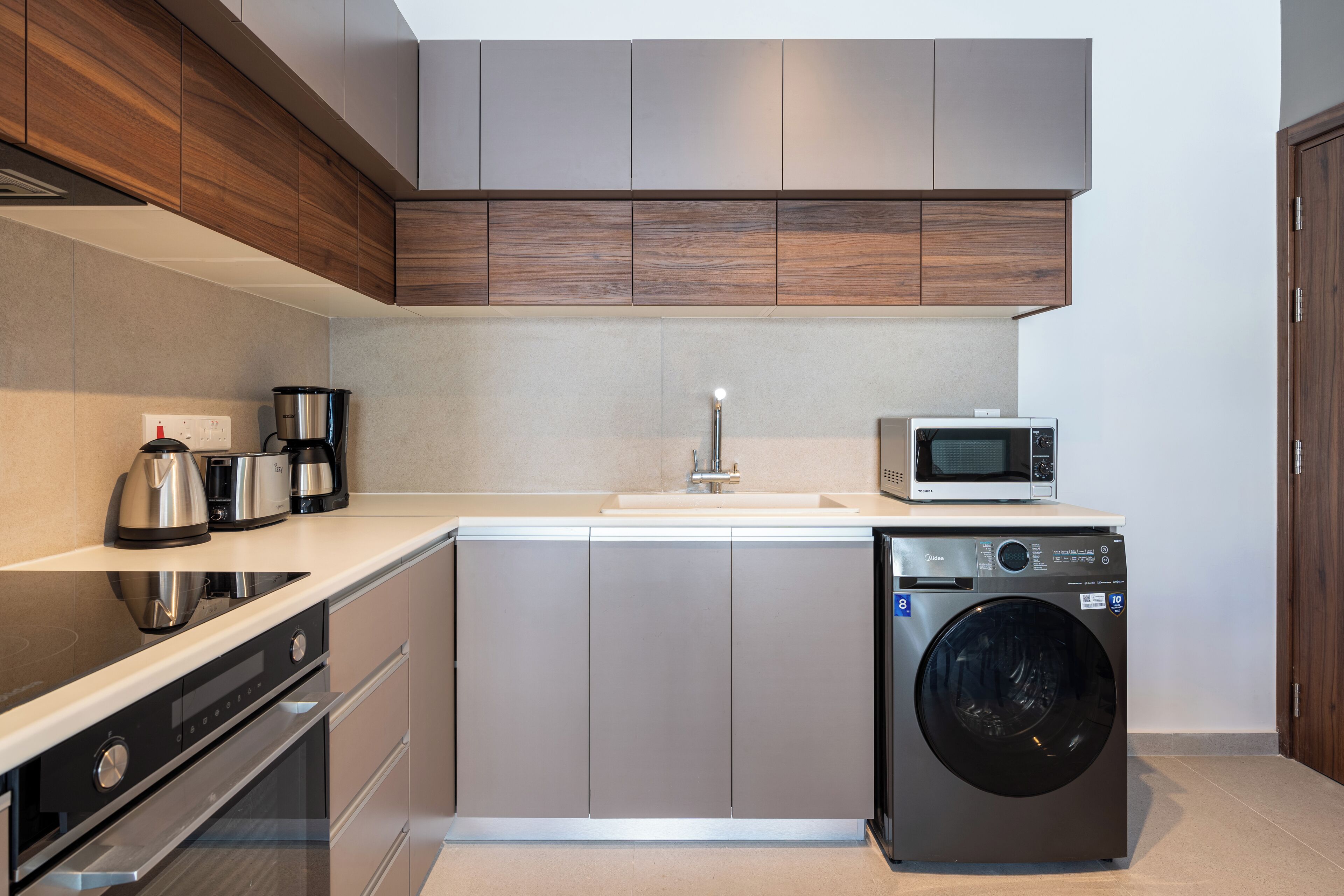 A modern kitchen with stainless steel appliances, a built-in oven, and a washing machine.
