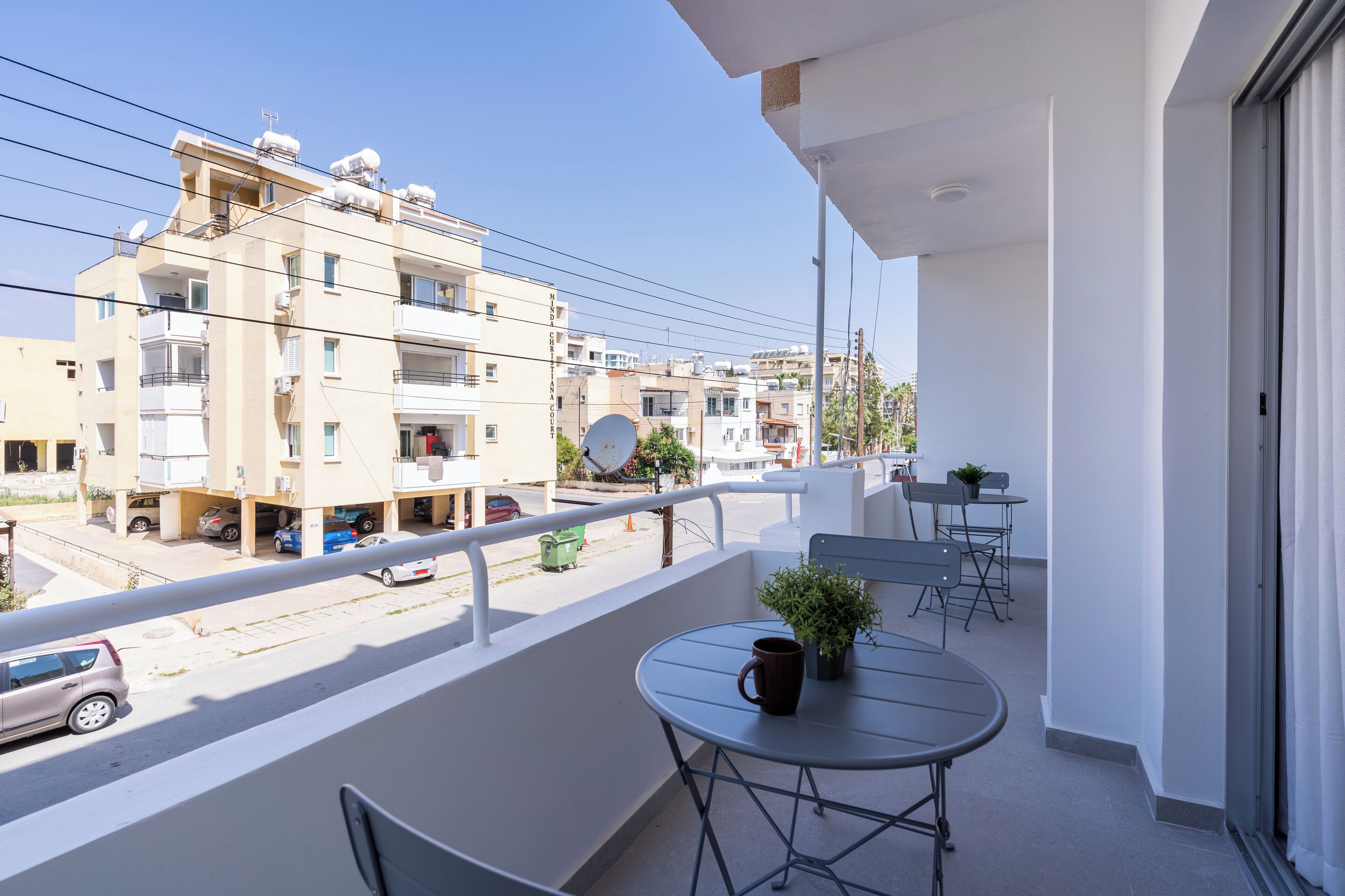 Un balcon avec une table, des chaises et un pot de fleurs.