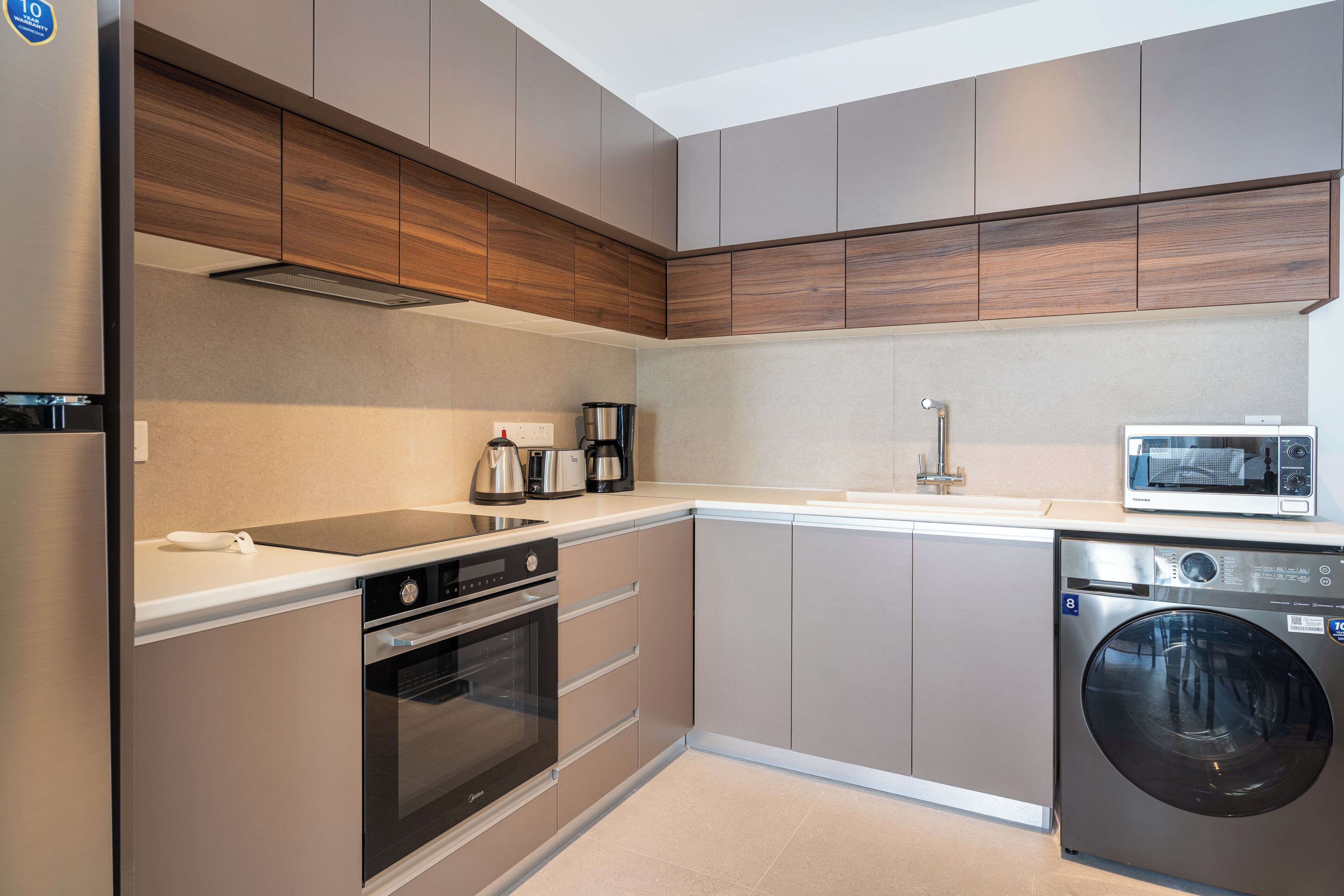 Een moderne keuken met een inbouwoven, magnetron en vaatwasser.