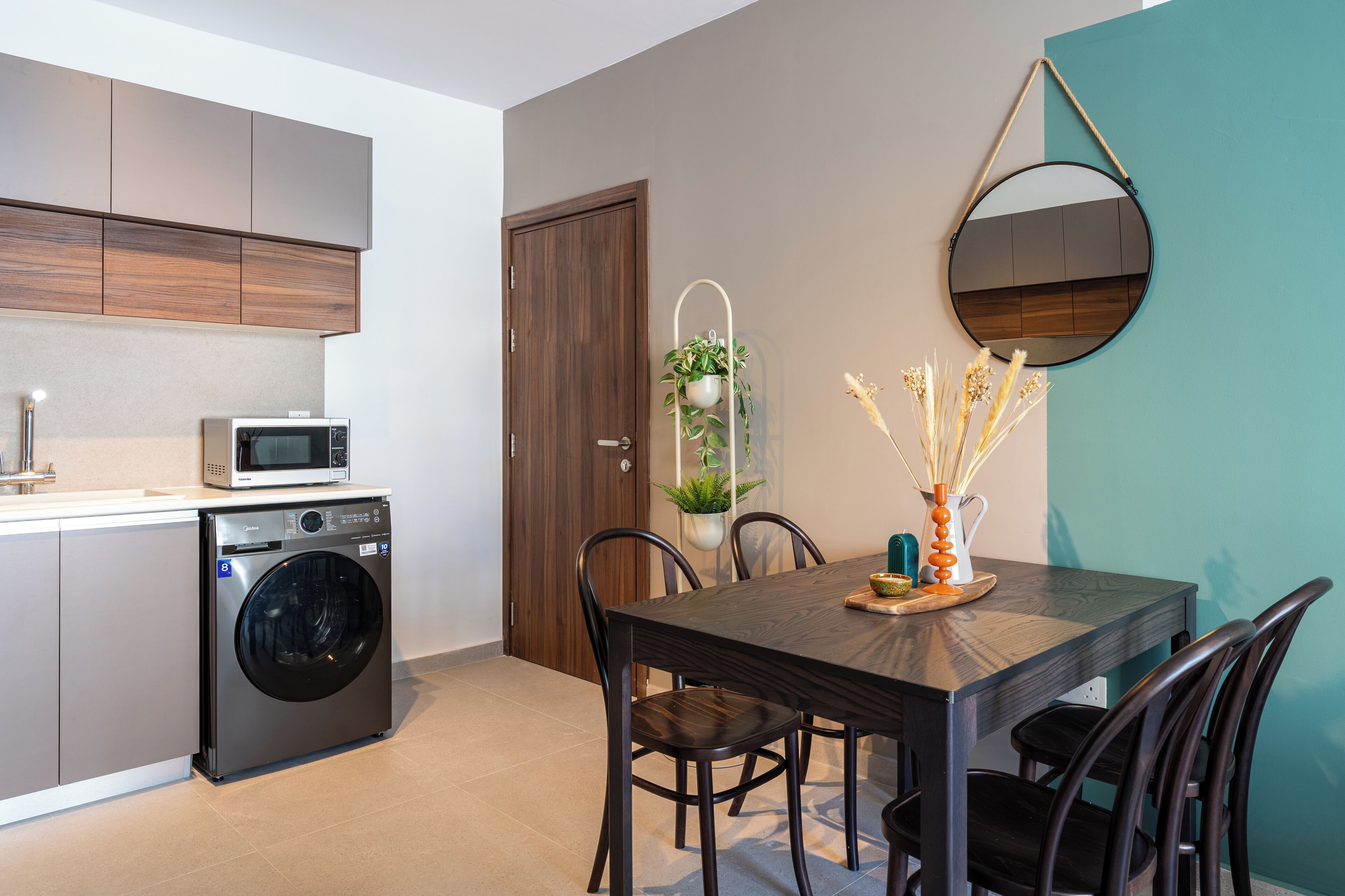 A compact kitchen with a washing machine, a microwave, and a dining area with a table and chairs.
