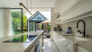 Een moderne keuken met een groot eiland, inbouwapparatuur en uitzicht op de tuin.