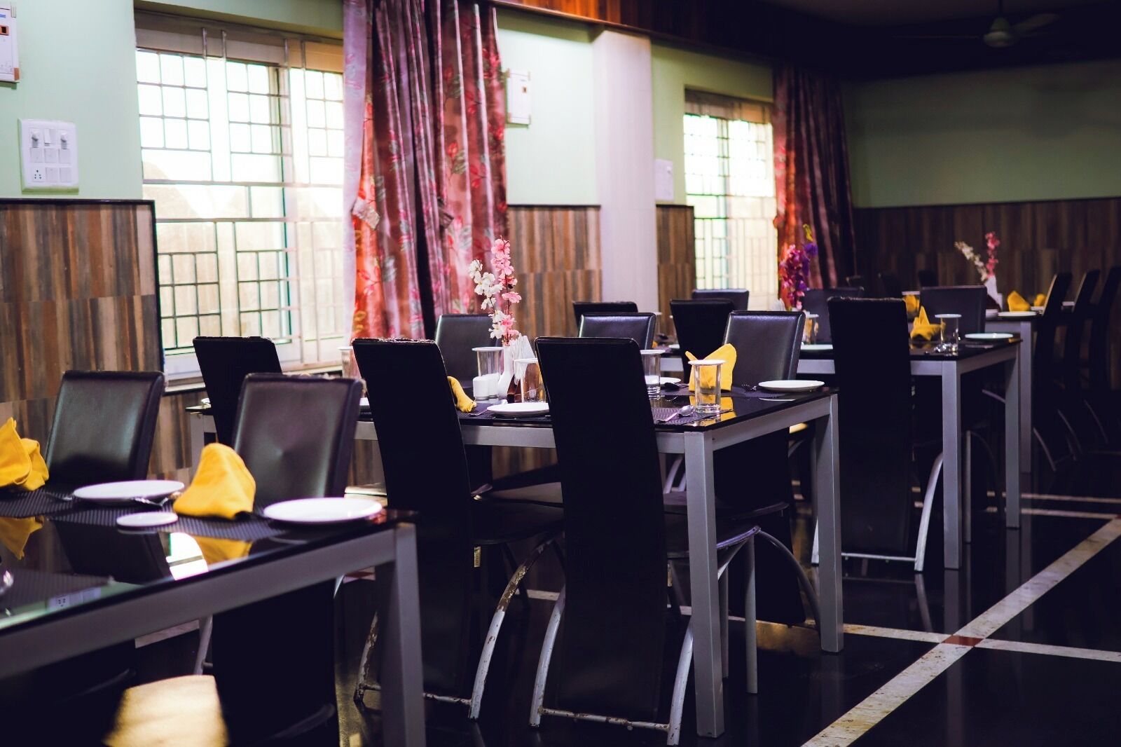 Sala de conferências com várias mesas e cadeiras, equipada com laptops e disposta para reuniões.