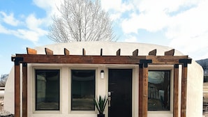 Un bâtiment moderne doté d’une pergola en bois, de grandes fenêtres et d’une plante en pot.