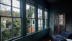 Une pièce dotée de grandes fenêtres, d’un plancher en bois et d’un canapé bleu.