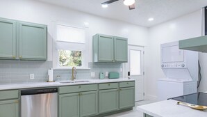 Une cuisine moderne avec des meubles de couleur verte, un lave-vaisselle, un four à micro-ondes et un four encastré.