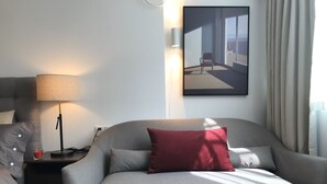 A modern hotel room with a grey sofa, a red pillow, a lamp, and a painting on the wall. - Innocondo Extended Stay Shanghai Changning Road (Shanghai)