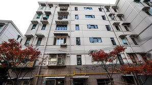 A multi-story residential building with balconies, a visible entrance, and a tree with red leaves in the foreground. - Innocondo Extended Stay Shanghai Changning Road (Shanghai)