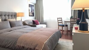 A hotel room with a large bed, a desk, a chair, a lamp, and a view of the outdoors. - Innocondo Extended Stay Shanghai Changning Road (Shanghai)