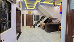 A hotel lobby with a reception desk, a staircase, and a chandelier. - Avadh Dham Guest House (Ayodhya)