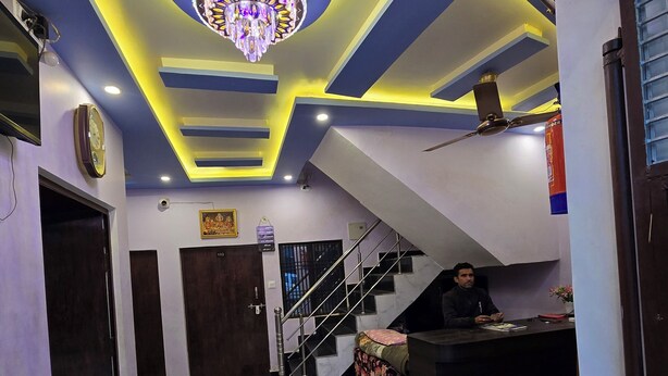 A hotel lobby with a marble floor, a reception desk, a staircase, and a chandelier. - Avadh Dham Guest House (Ayodhya)