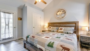 Een slaapkamer met een bed, een plafondventilator, een deur, een wandklok en een raam met gordijnen.