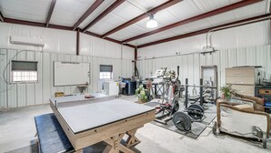 A spacious industrial room with a large workbench, exercise equipment, and a whiteboard. - Large Patio & Grill! Group Stay in Midland (Midland)