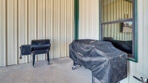 A covered grill and a small black object against a corrugated metal wall. - Large Patio & Grill! Group Stay in Midland (Midland)