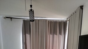 A room with a patterned rug, a flat-screen TV, a ceiling light fixture, and a window with curtains. - Spacious 3-bedroom apartment in phenomenal Alexandria Governorate with AC (Alexandria Governorate)