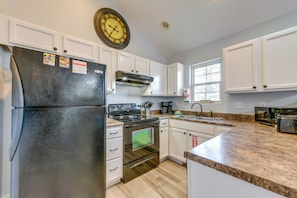 A kitchen with white cabinets, a black refrigerator, a stove, and a microwave.