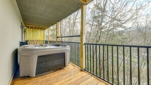 A wooden deck with a hot tub, a railing, and a view of trees. - Mtn Views & Hot Tub: Modern Gatlinburg Townhome (Gatlinburg)