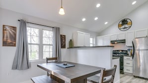 Una cocina con una mesa de madera, armarios blancos y un refrigerador de acero inoxidable.