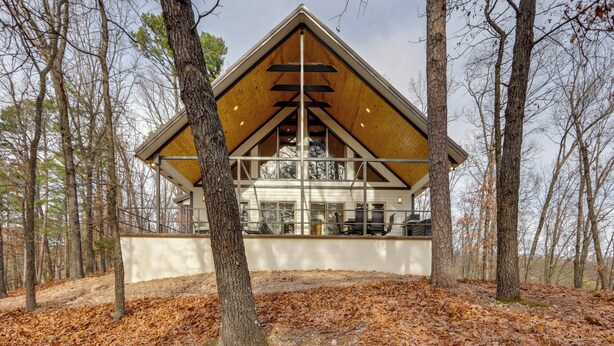 A cabin with a triangular roof, large windows, and a view of the surrounding forest. - Epic Lake Views! 'The Ridge' Eureka Springs Home (Eureka Springs)