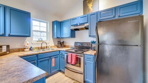 Eine Küche mit blauen Schränken, Edelstahlgeräten, einem Kühlschrank und einem Fenster.