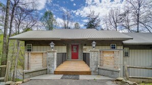 Ein Chalet mit roter Tür, einer Holzrampe und einer Steinmauer.