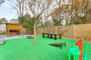 An outdoor play area with green turf, wooden tables, and a wooden play structure. - Sand Volleyball Court, Pool, Hot Tub! Fun Retreat (Savannah)