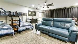 A room with bunk beds, a blue leather sofa, a ceiling fan, and a billiards sign. - Sand Volleyball Court, Pool, Hot Tub! Fun Retreat (Savannah)