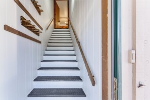 A staircase with wooden handrails and a metal banister, leading to an interior space.