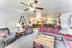 A living room with a sofa, armchairs, a coffee table, and a ceiling fan.