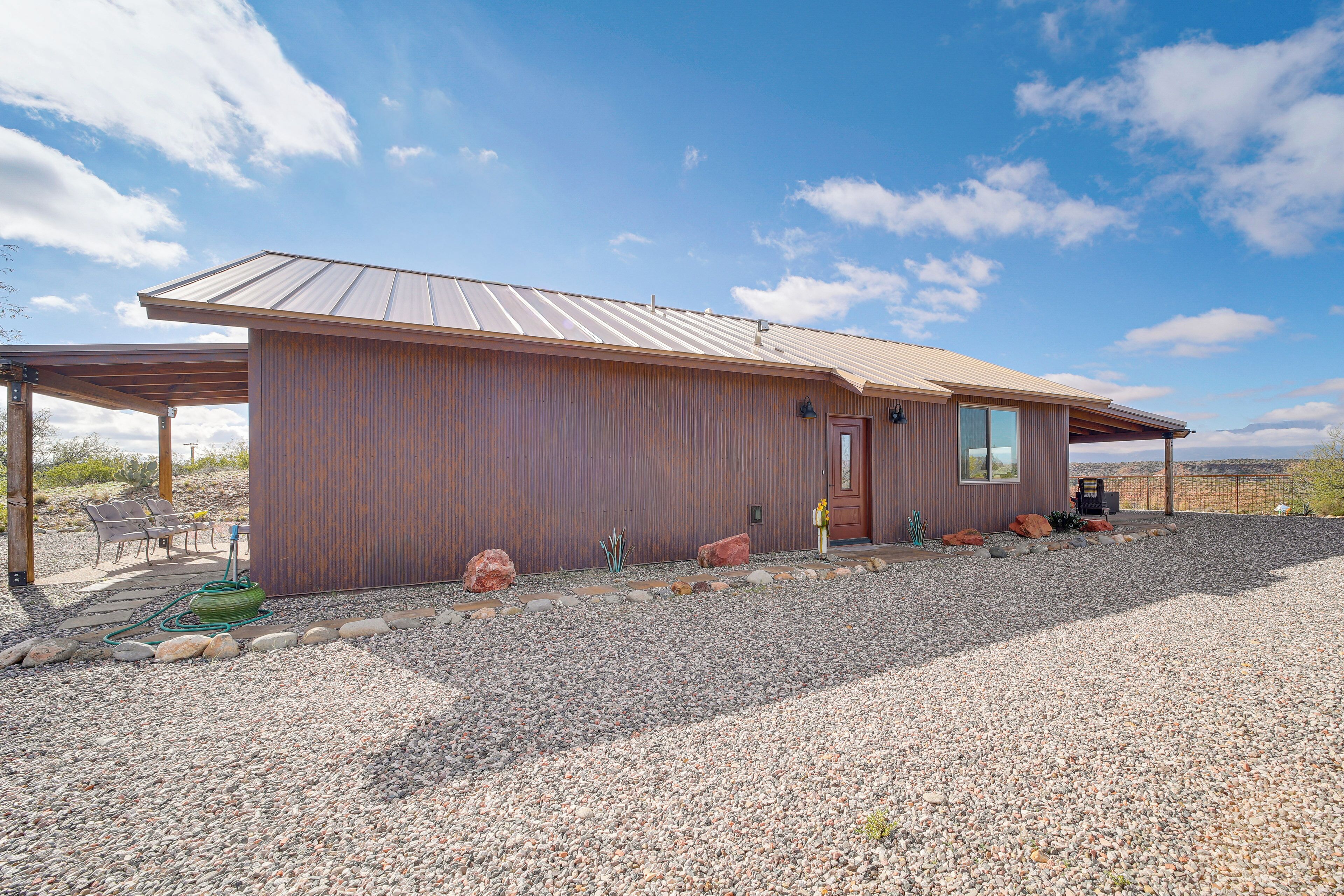 A single-story building with a metal roof, a wooden exterior, and a gravel driveway.