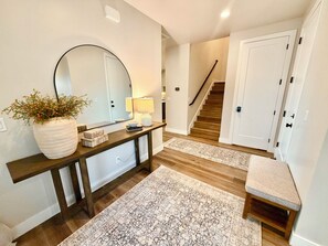 A hallway with a wooden console table, a large mirror, a potted plant, a lamp, and a patterned rug. - Luxury Home near Zion NP! Resort Pools Open Year-Round! (Washington)