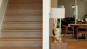 Una escalera de madera que conduce a un comedor con una mesa y sillas.