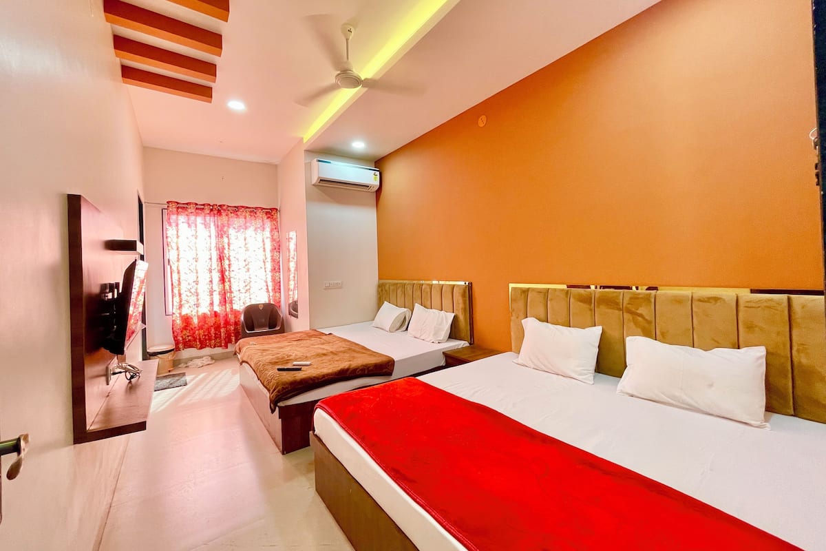 Une chambre d’hôtel avec deux lits, un ventilateur de plafond, un appareil de climatisation et un miroir.