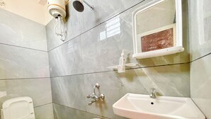 Een badkamer met toilet, wastafel, douche en emmer.