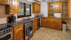 Una cocina con muebles de madera, lavadora, estufa y fregadero.