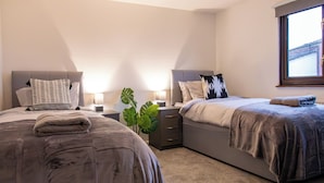 Un dormitorio moderno con dos camas, un ventanal grande y una lámpara de techo.