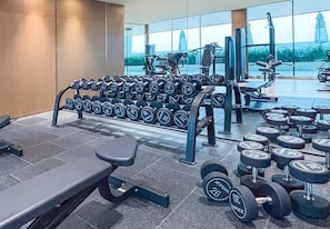 Ein Fitnessstudio mit Krafttrainingsgeräten, Kurzhanteln und Bänken.