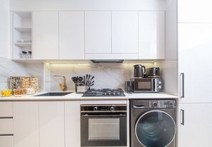 Eine moderne Küche mit weißen Schränken, einem Backofen, einer Mikrowelle und einem Geschirrspüler.
