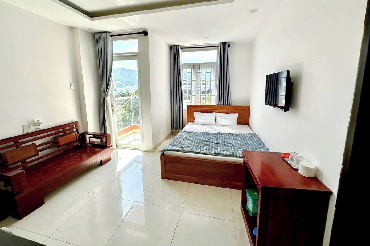 Een hotelkamer met een bed, een houten bankje, een kleine tafel en een televisie.
