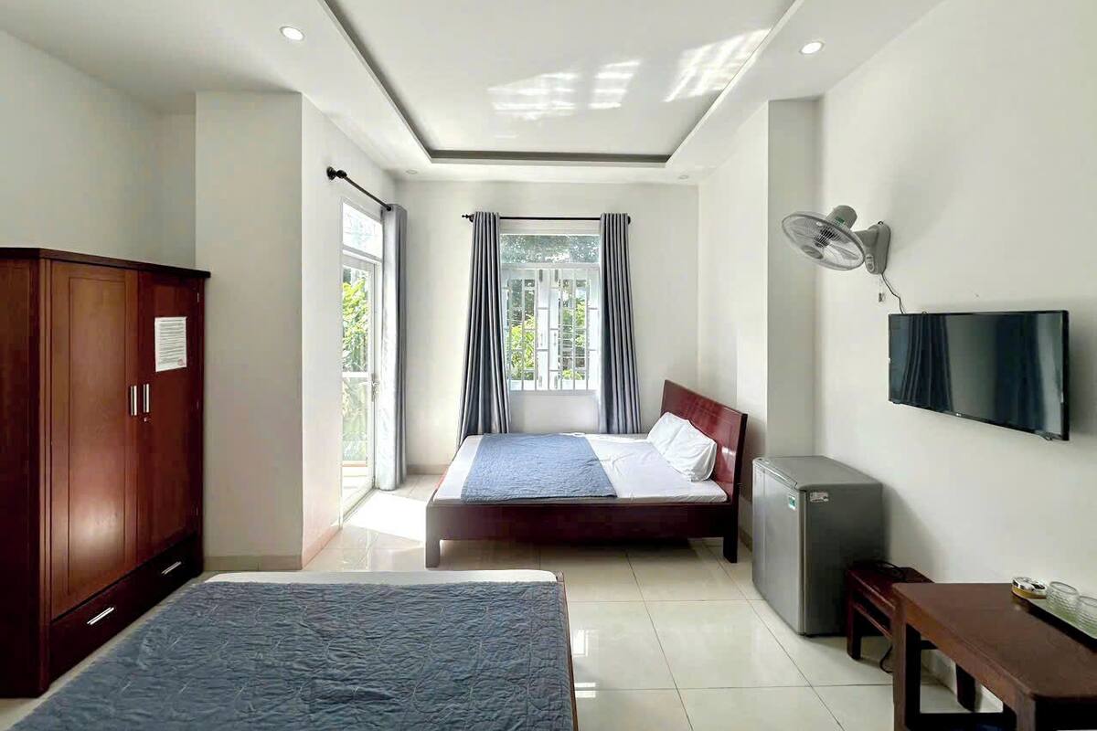 Een hotelkamer met een bed, een bureau, een kledingkast, een televisie en een raam met gordijnen.