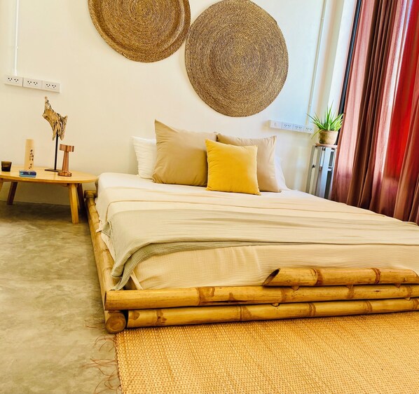 A bed with a bamboo frame, a woven rug, and a bedside table with a plant.