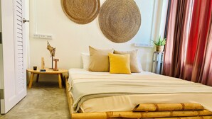 Ein ordentlich eingerichtetes Schlafzimmer mit einem Bett, Kissen, einem kleinen Tisch mit Lampe und einer Wandsteckdose.