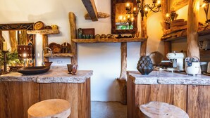A rustic kitchen with wooden stools, a wooden counter, and various kitchen items. - The Pool House - Organic Charm & Pool (Goult)