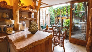 A rustic kitchen with wooden beams, a stone countertop, and a view of a lush garden through a glass door. - The Pool House - Organic Charm & Pool (Goult)