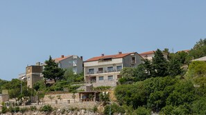 Zona residencial costera con edificios de varios pisos, muros de piedra y abundante vegetación.
