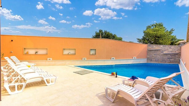 A swimming pool with lounge chairs and a stone wall. - Apartman Damir 1 by Villas Guide (Galižana)