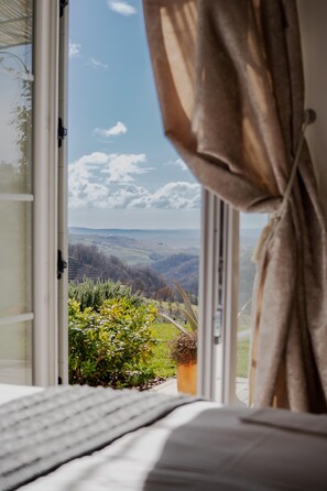 Ein Schlafzimmer mit einem Fenster, das auf eine Landschaft blickt.