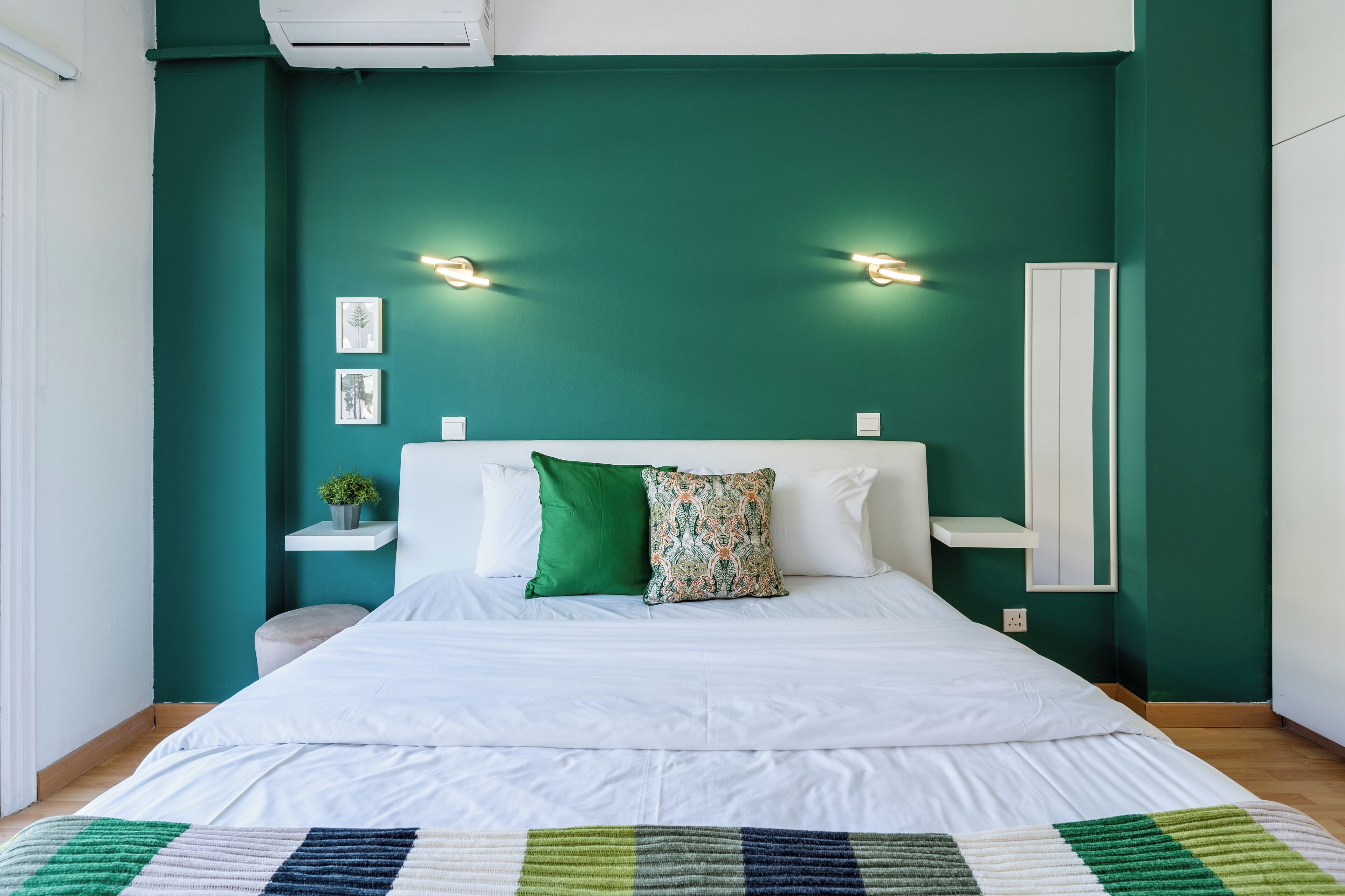 Ein Schlafzimmer mit einem Bett, grünen Wänden und einem weißen Kopfteil.
