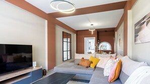 A modern living room with a large flat-screen TV, a sofa with multiple cushions, and a coffee table. - Oracle 2-BR Apt. & Balcony in Larnaca (Larnaca)