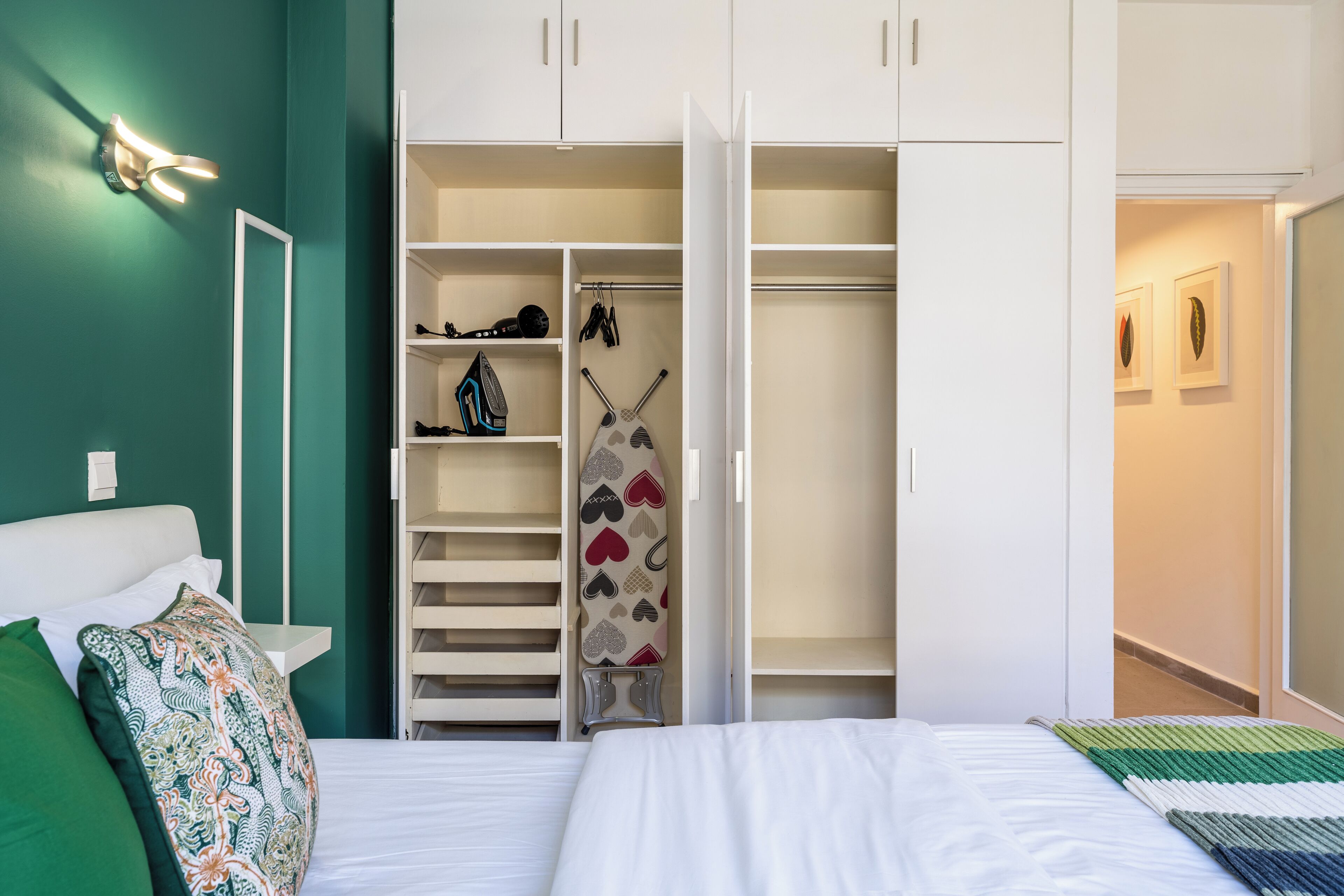 Une chambre à coucher comprenant un lit, une armoire et un placard avec des étagères et une tringle pour suspendre les vêtements.