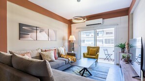 A modern living room with a sofa, a coffee table, a yellow armchair, and a TV. - Oracle 2-BR Apt. & Balcony in Larnaca (Larnaca)